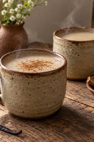 Warm vanilla atole in handmade ceramic mugs with cinnamon