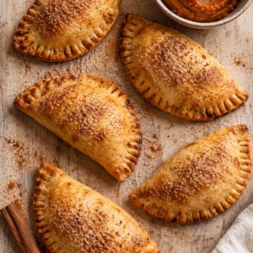 Golden baked pumpkin empanadas with fork-crimped edges and cinnamon sugar.
