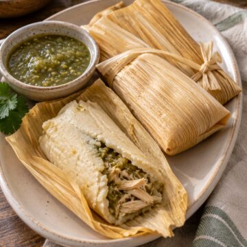 Corn-husk tamales with chicken and green salsa in tender masa.